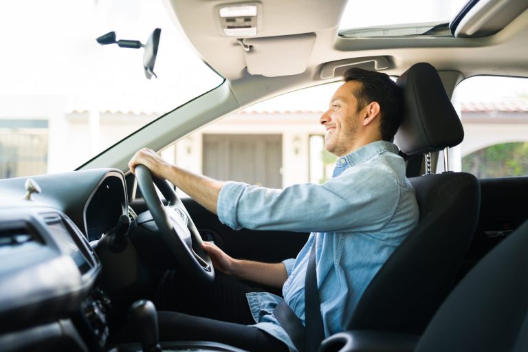 Kierowca uber uśmiecha się podczas proiwadzenia taxsówki wraz z klientem firmy Gocab,