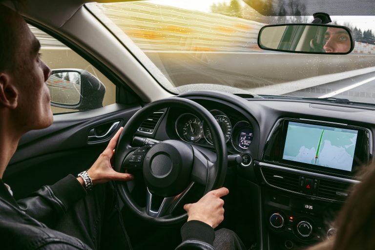 Młody mężczyzna prowadzi samochód osobowy z navigacją, kierowca zatrudniony upartnera wflotowego bolt, uber, free now - Gocab