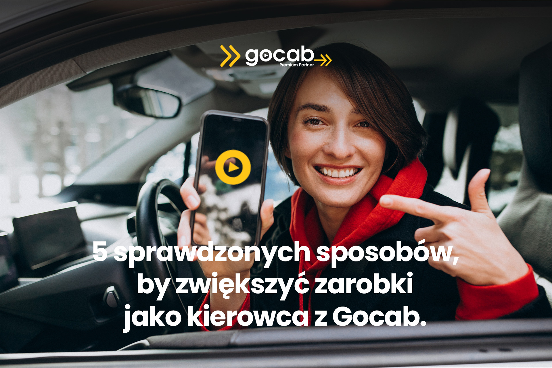 Kobieta kierowca Gocab uśmiecha się i pokazuje aplikację taxi na smartfonie, siedząc za kierownicą samochodu. Praca kierowcy Uber, Bolt i FreeNow w Trójmieście – Gdańsk, Gdynia, Sopot. Elastyczna praca z wysokimi zarobkami jako kierowca z Gocab Premium Partner.